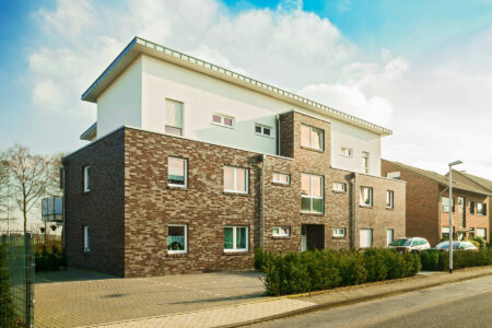 Ein großes Mehrfamilienhaus in Reichswalde/Materborn mit Fenstern von HG RaumDesign