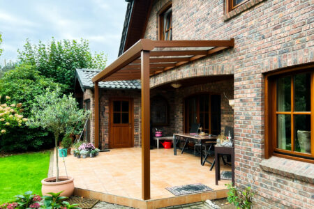Kleine Terrassenüberdachnung mit Profilen in Holzoptik an einem Haus im Landhaus-Stil