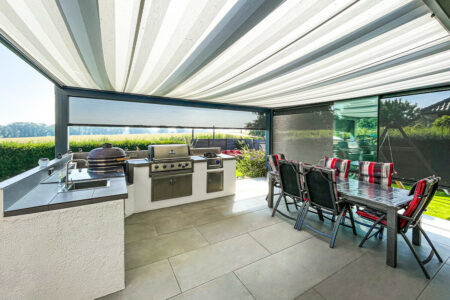 Zipscreens mit unterschiedlichen Lichtdurchlässigkeiten bei einer großen Terrassenüberdachung für eine hochwertige Outdoor-Küche