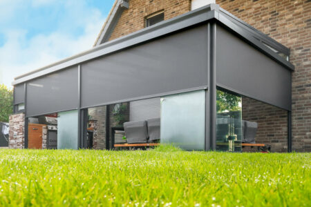 Perfektes Outdoor-Living mit Lounge, Esstisch und Outdoorküche unter einer Terrassenüberdachung mit Glasschiebe-Elementen und Zipscreens