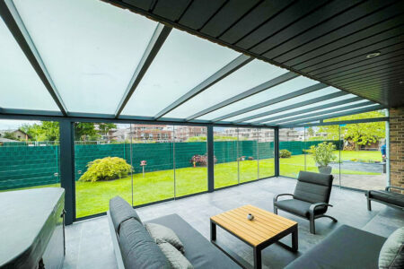 Innenansicht einer sehr großen Terrassenüberdachung mit Panorama-Blick ins Grüne dank umlaufender Glasschiebewände