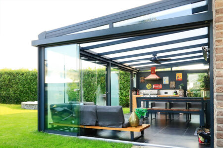 Terrasse mit Outdoorküche und Terrassendach mit Glasschiebewänden und vertikalen Zipscreens von HG RaumDesign